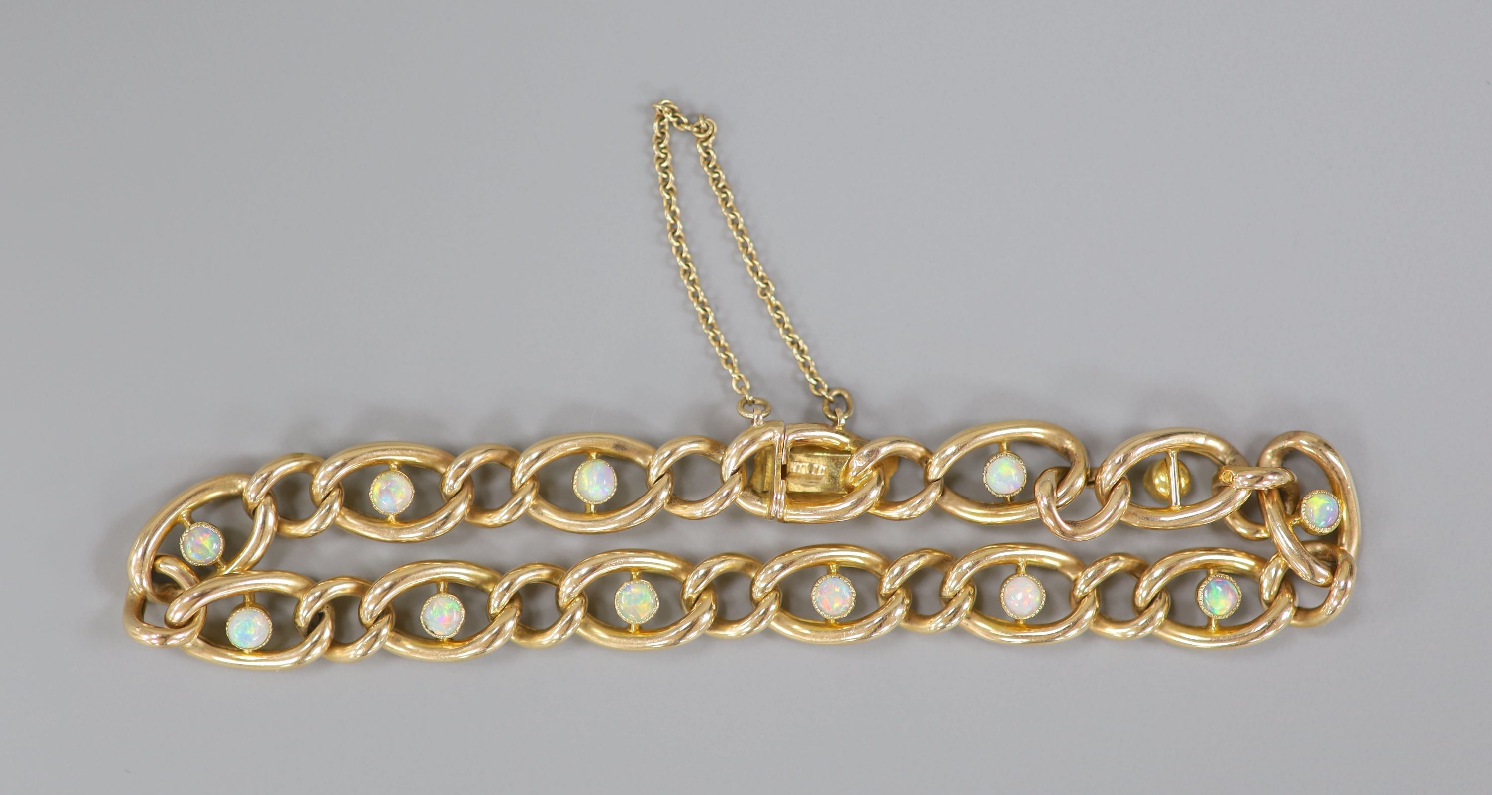 An early 20th century yellow metal and twelve stone white opal set oval link bracelet, 19cm, gross 11.9 grams.